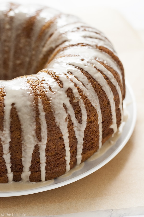 An angle shot of the side of a pumpkin bundt cake with glaze on on the sides of it.