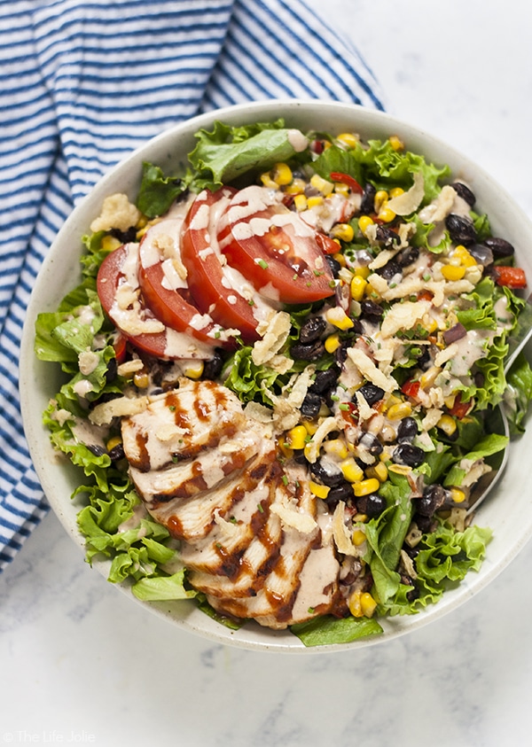 An overhead image of Panera bbq chicken salad in a white bowl with a blue and white stripe napkin next to it.