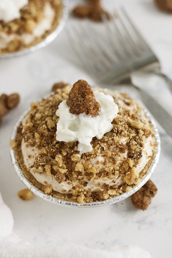 Make this Mini Pumpkin Cheesecake Recipe for the holidays- they're no-bake, seriously easy and totally delicious! Made with pumpkin yogurt, cream cheese, powdered sugar, pumpkin pie spice and vanilla in a graham cracker crust with candied pecans on top, these are sure to please the whole family!