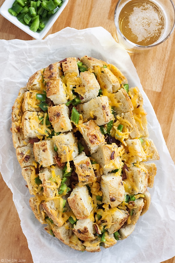 This cheesy Jalapeno Popper Pull Apart Bread is an easy recipe for game day! A loaf of bread stuffed with jalapenos, cheese and bacon; it's super quick to throw together and is sure to be a hit at your next Superbowl Party!
