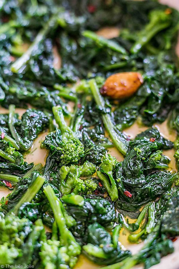 A close up view of broccoli rabe with garlic in a saute pan.
