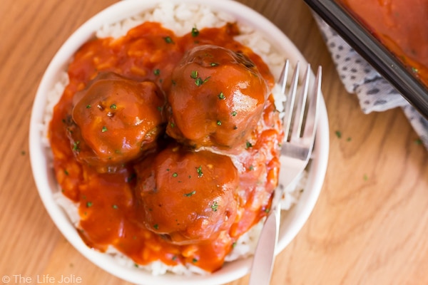 An overhead image of a plate of three Classic Porcupine Meatballs on white rice in a white plate.