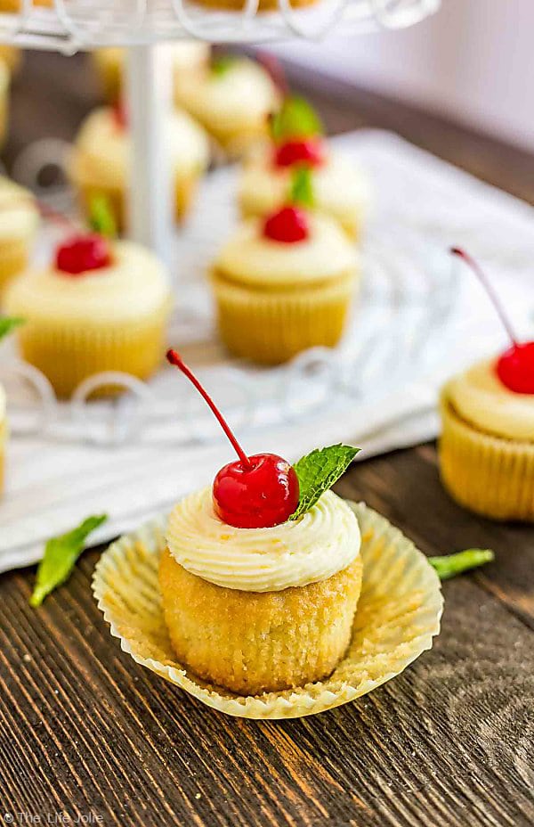 A Mai Tai Cupcake in the front with the cupcake wrapper loosened off the sides and other Mai Tai Cupcakes in the background.