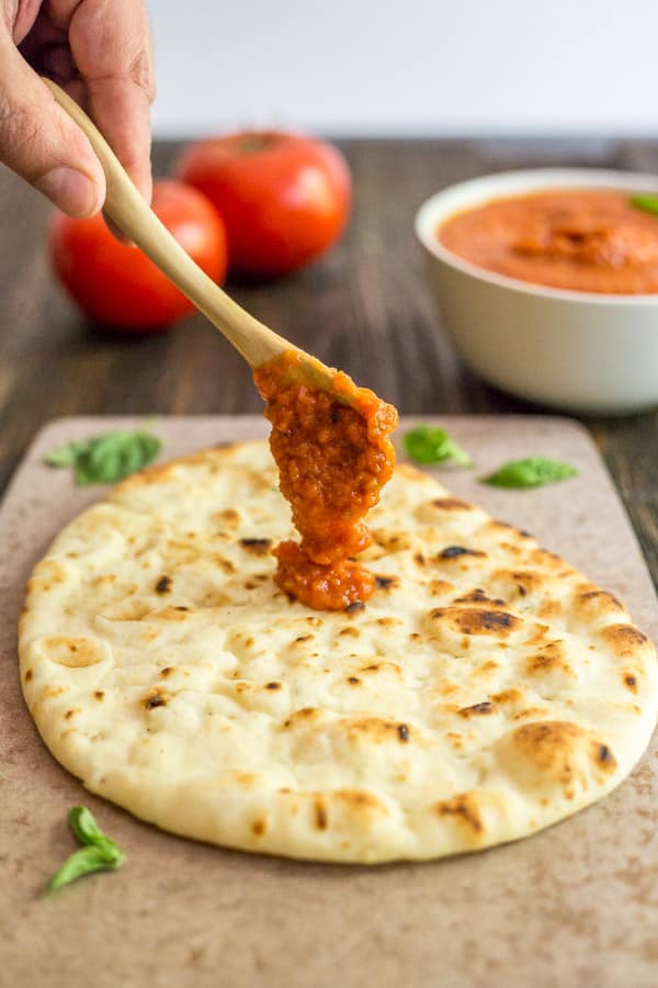 Easy Pizza Sauce being spooned on to flat bread.