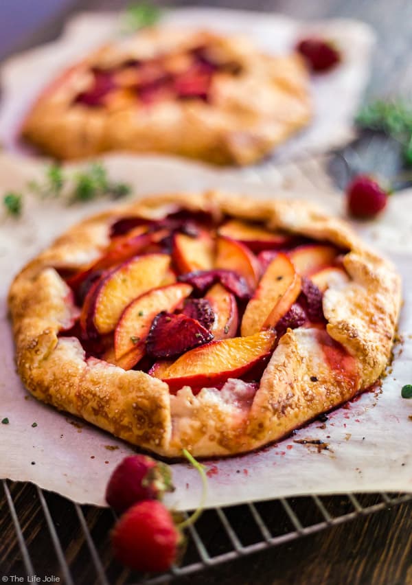 Nectarine and Strawberry Galette with Thyme in the foreground with another out of focus behind it.