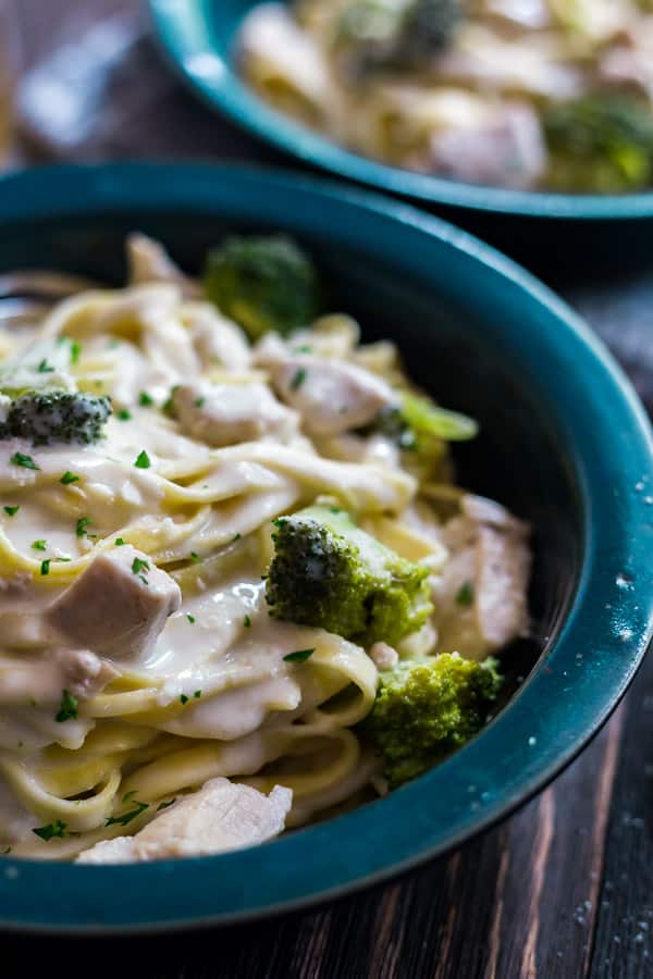 A close up image of one side of Creamy Chicken and Broccoli Pasta with another bowl of it ourt of focus in the background.