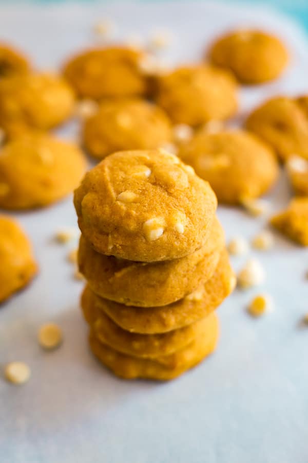 A stack of White Chocolate Macadamia Nut Pumpkin Cookies taken frm a high angle with other cookies in the background.