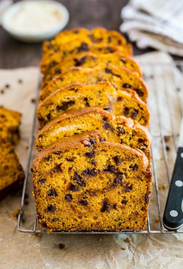 Pieces of Pumpkin Chocolate Chip Bread lined up on a coolnig rack with the front one in focus.