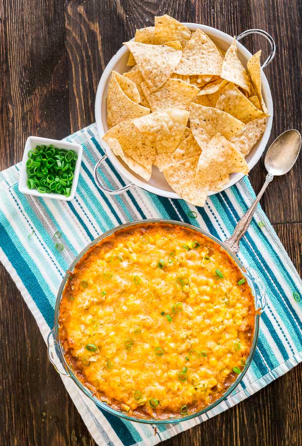 An overhead image of Hot 7 Layer Bean Dip with chips and green onions on the side.