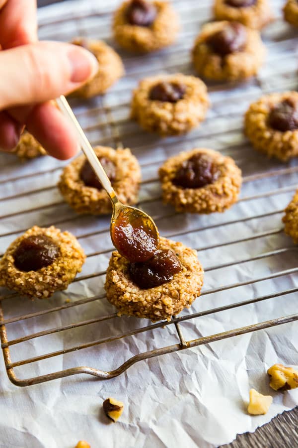 A spoon putting apple butter into Apple Cinnamon Thumbprint Cookies.