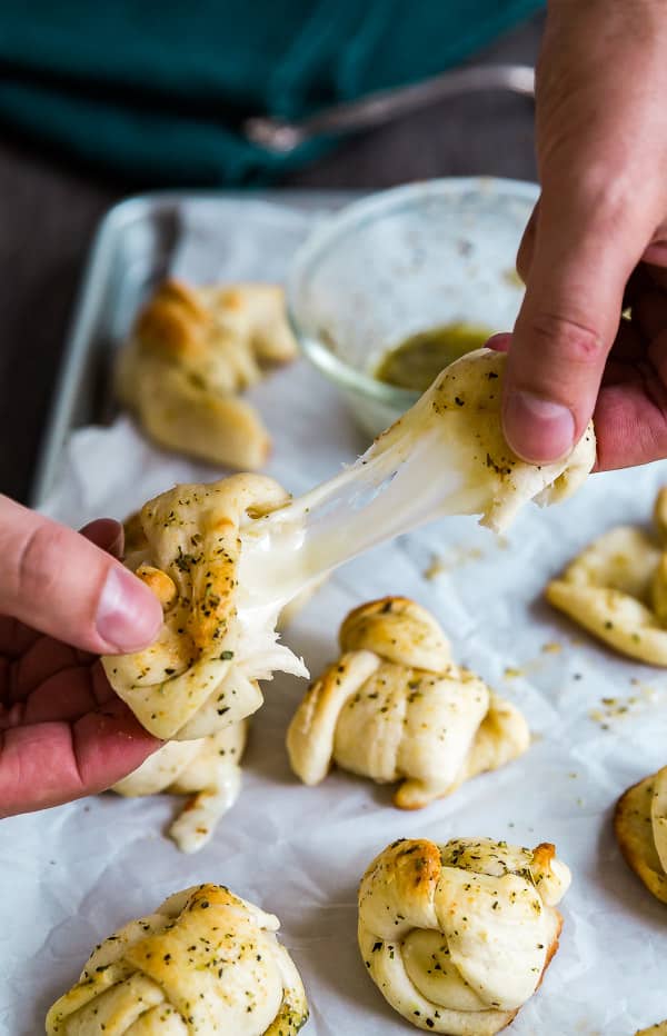 Hands stretching a Cheesy Garlic Knot.