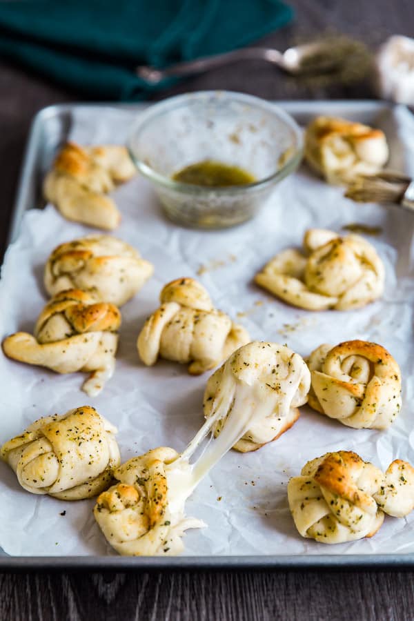 Cheesy Garlic Knots on a pan with a cheese stretch up front.